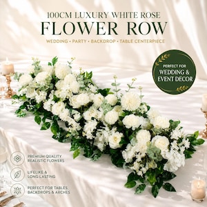 May include: A 100cm luxury white rose flower row featuring a dense arrangement of white roses, pom-pom style flowers, and green eucalyptus leaves. The text 100CM LUXURY WHITE ROSE FLOWER ROW WEDDING PARTY BACKDROP TABLE CENTERPIECE is visible.