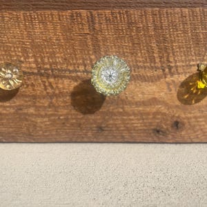 May include: A white ceramic mug with a black handle and the text "But First, Coffee" in a bold, black font. The mug is set against a blurred background, highlighting its clean design.