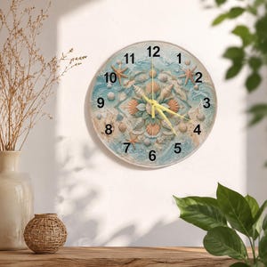 Può includere: Un orologio da parete rotondo con un design a mandala costiero composto da varie conchiglie, stelle marine e onde oceaniche azzurre. Il quadrante presenta numeri arabi neri da 1 a 12 e tre lancette gialle per indicare l'ora.