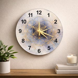 Può includere: Orologio da parete rotondo con un design blu e oro. Il quadrante presenta un motivo geometrico e numeri e lancette dorate. L'orologio è montato su una parete chiara, con una pianta e una candela in primo piano.