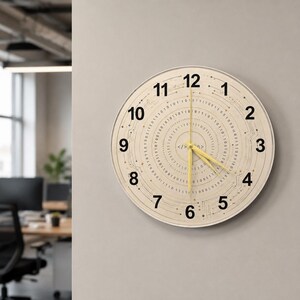 May include: A round wall clock with a cream-colored face and black numerals. The clock features a circuit board design with binary code and yellow hands. The clock is mounted on a gray wall.