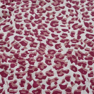May include: A white fabric with a pink leopard print pattern.