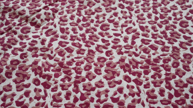 May include: A white fabric with a pink leopard print pattern.