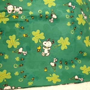 May include: Green fabric featuring Snoopy and Woodstock characters, shamrocks, and the text "Happy St. Patrick's Day" in a repeating pattern. The design includes Snoopy wearing a green hat.