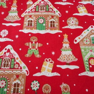 May include: A festive red fabric featuring a repeating pattern of gingerbread houses, gingerbread men, Christmas trees, and wrapped gifts. The houses have white icing roofs and are decorated with candy canes and other sweets. Snowflakes are scattered across the design.