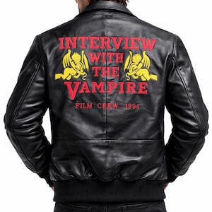 May include: Black leather bomber jacket with red and yellow embroidered text and graphics on the back. The text reads "INTERVIEW WITH THE VAMPIRE FILM CREW 1994". The jacket has a ribbed hem and cuffs.