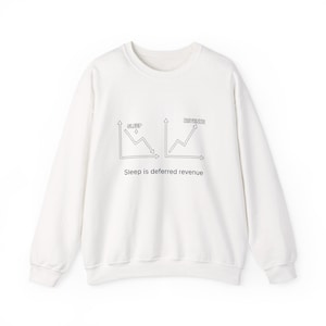 May include: White crew neck sweatshirt with a black graphic. The graphic features two charts with the words "SLEEP" and "REVENUE" above them, and the text "Sleep is deferred revenue" below. A casual, comfortable garment.
