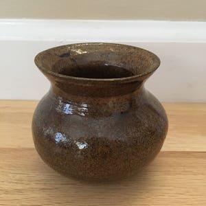 May include: A small, brown ceramic vase with a speckled glaze.