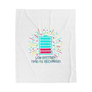 Peut inclure: Couverture blanche ornée d'un motif coloré. Le motif représente une icône de batterie faible en bleu sarcelle et rouge, avec le texte "LOW BATTERY: TIME TO RECHARGE!". L'icône est entourée de formes géométriques.