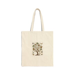 May include: Cream-colored tote bag featuring a detailed illustration of a tree with various botanical elements. The design includes butterflies, leaves, and other natural motifs, creating a nature-themed accessory.