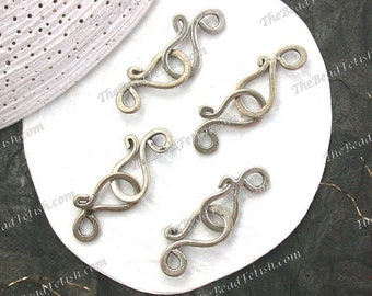 May include: Five silver-toned metal clasps with a decorative, swirling design. The clasps are arranged on a white surface.
