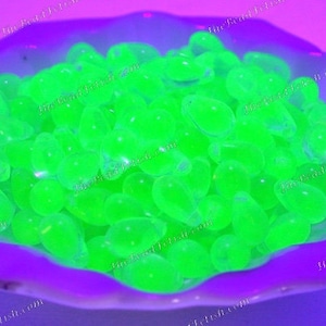 May include: A bowl filled with bright green glow-in-the-dark glass pebbles. The pebbles are smooth and oval-shaped.