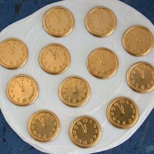 May include: A white surface with twelve gold-coloured clock faces, each with Roman numerals and black hands.