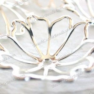 May include: Silver metal flower-shaped bead cap with a delicate, openwork design. The cap has a round hole in the center for attaching to a bead or other jewelry component.