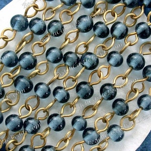 May include: A strand of dark blue glass beads strung on a gold chain. The beads are round and have a slightly textured surface.