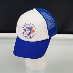 May include: A blue and white baseball cap with a mesh back. The front of the cap features a logo with a blue jay, a maple leaf, and the words "POMPANO BEACH BLUE JAYS". The brim is blue.