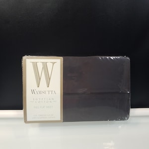 Puede incluir: Una sábana plana de color gris oscuro empaquetada. El embalaje incluye una etiqueta con la marca "Wamsutta" y el texto "Egyptian Cotton" y "Full Flat Sheet". La etiqueta también indica que tiene 250 hilos y está hecha de 100% algodón egipcio.