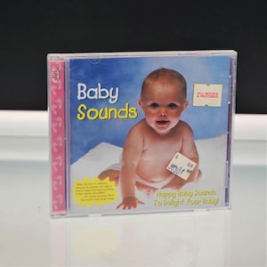 May include: A clear plastic CD case featuring the Baby Sounds album cover. The cover displays a baby on a white surface against a blue background, with the text Baby Sounds, Happy Baby Sounds To Delight Your Baby!, and a yellow starburst quote.
