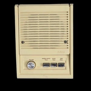 May include: A beige NuTone wall-mounted intercom unit featuring a rectangular speaker grille, a circular silver volume knob, and three rectangular push buttons labelled Inside/Patio Talk, Door Talk, and End Call, all set in a plastic housing.
