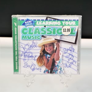May include: A CD case for "Learning Your Classic Music" by Baby Scholar. The cover features a smiling girl in a straw hat holding a conductor's baton. The CD case has the text "Music for the Developing Mind" and lists composers Vivaldi, Mozart, and Beethoven.