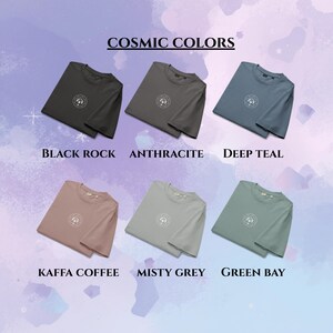 May include: A collection of six folded t-shirts in various colors, including black, gray, teal, pink, light gray, and green. Each shirt features a circular design and is labeled with its color name. The text "Cosmic Colors" is at the top.