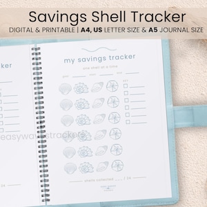 May include: A light blue journal with a spiral binding, open to reveal a savings tracker with seashell illustrations. The text "Savings Shell Tracker" is at the top. The journal is on a sandy surface with seashells.