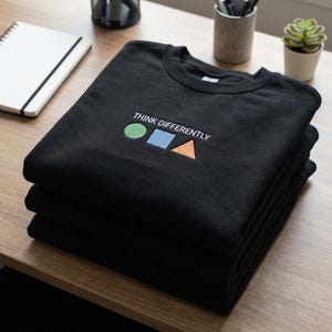 May include: A set of three ceramic mugs with a speckled, cream-colored glaze. Each mug features a different hand-painted floral design in shades of blue, green, and yellow. The mugs have a simple, modern shape.