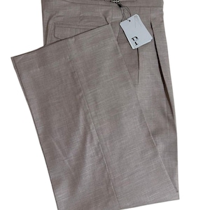 May include: Taupe-coloured dress trousers with a pleated front and a tailored fit. The trousers feature a belt loop with a decorative buckle and a tag attached. The fabric has a subtle texture, suggesting a high-quality material.