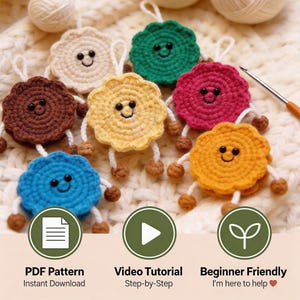 May include: A collection of colorful, handmade crochet ornaments in various colors, including yellow, blue, brown, green, and pink. Each ornament has a smiling face and small dangling legs. The image also includes text that says "PDF Pattern", "Video Tutorial", and "Beginner Friendly".