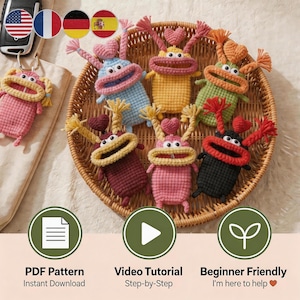 May include: A collection of colorful, handmade crochet keychains shaped like whimsical creatures with heart-shaped antennae and large, smiling mouths. The keychains are in a woven basket, with a pink keychain on the left. The image also includes icons for a PDF pattern, video tutorial, and beginner-friendly instructions.
