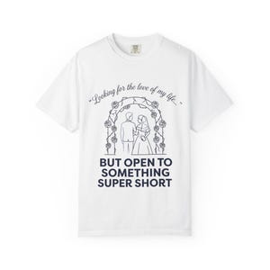 Może przedstawiać: Biała koszulka z granatową grafiką. Grafika przedstawia parę pod kwiatowym łukiem i tekst: "Looking for the love of my life... BUT OPEN TO SOMETHING SUPER SHORT."
