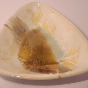 May include: A triangular ceramic bowl featuring a glossy off-white glaze with crystalline patterns in shades of golden brown and soft blue. The interior surface displays a prominent, starburst-like crystalline formation centered in the middle.