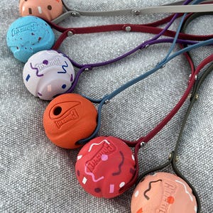 May include: A collection of six spherical dog toys, each featuring the embossed text Chuckit! and attached to a long, flexible handle. The balls come in various colours including peach, blue, white, orange, and red, with some featuring confetti patterns.