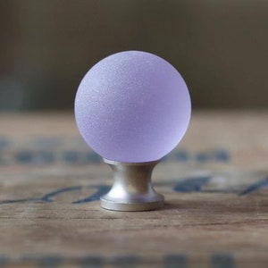 May include: A frosted glass cabinet knob in a light purple color with a silver base.