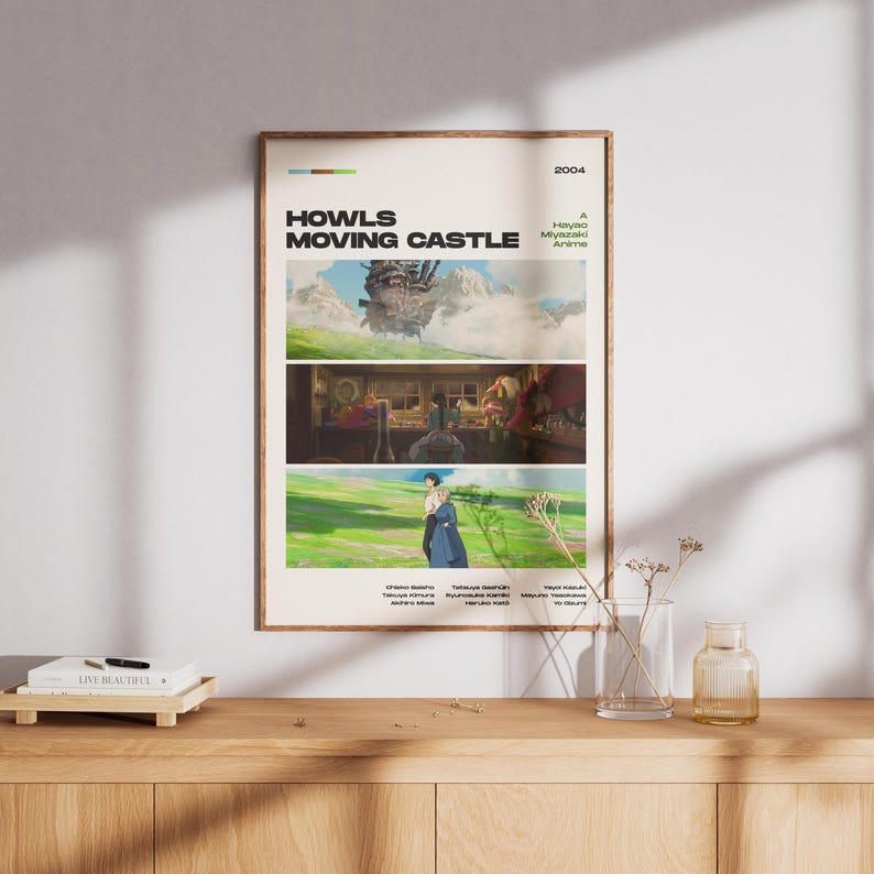 May include: A framed poster featuring scenes from the animated film "Howl's Moving Castle." The poster has a beige background with three horizontal panels showcasing different scenes. The title and year are displayed at the top.