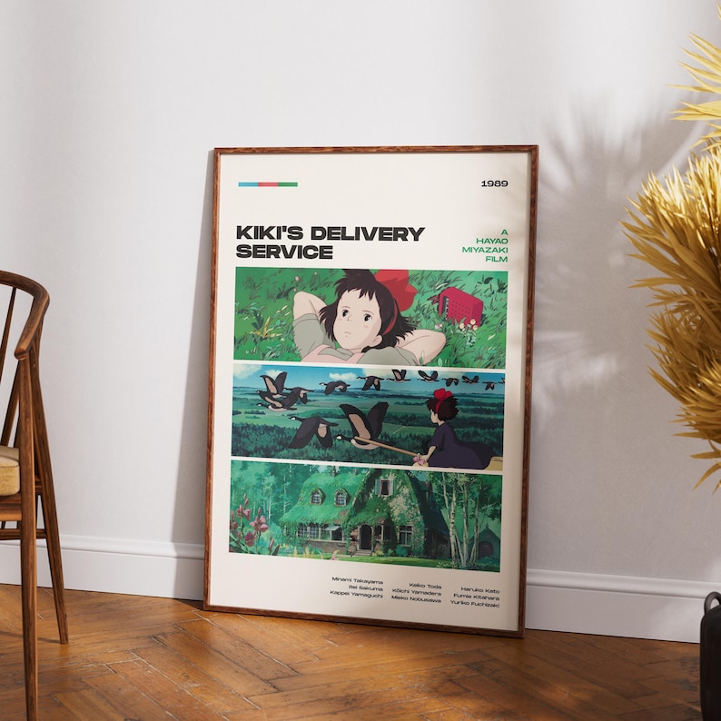 May include: A framed poster for the animated film "Kiki's Delivery Service" by Hayao Miyazaki. The poster features three panels with illustrations of the main character, Kiki, and scenes from the movie. The poster is in a wooden frame and leans against a wall.