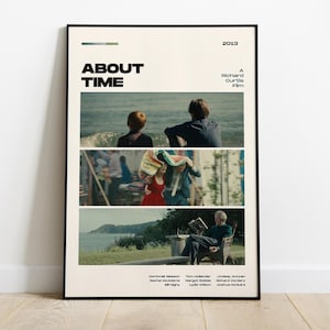 Op de afbeelding: Ingelijste filmposter voor "About Time" met een crèmekleurige achtergrond. De poster bevat drie horizontale afbeeldingen uit de film. De titel "ABOUT TIME" staat bovenaan, met het jaar 2013. De poster wordt op een houten vloer getoond.