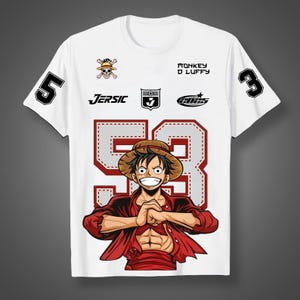 May include: White t-shirt featuring a cartoon illustration of a character with a straw hat and red shirt. The number "53" is prominently displayed on the front, with the number "5" and "3" on the sleeves. The text "Monkey D Luffy" is printed on the shirt.