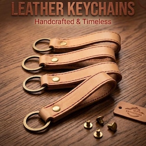Op de afbeelding: Leren sleutelhangers in een bruine kleur met de tekst "Leather Keychains Handcrafted & Timeless". Ze hebben messing ringen en klinknagels. De naden zijn rood. Een klein leren label is ook zichtbaar.