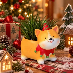 May include: A yellow corgi-shaped planter featuring a red and green elf hat and a matching red collar with green pom-poms. The ceramic dog figure has white paws and a small tongue sticking out, holding a cluster of green grass-like foliage inside.