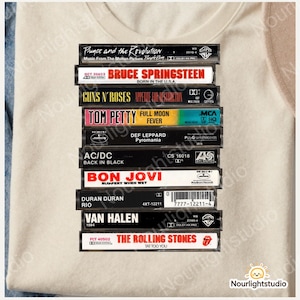 May include: A collection of classic cassette tapes, including albums by Prince, Bruce Springsteen, and The Rolling Stones. The tapes are stacked, displaying band names and album titles, evoking a sense of nostalgia.