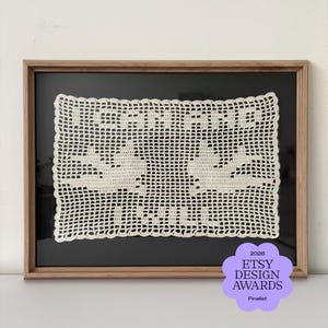 May include: A rectangular off-white crochet doily featuring two bird silhouettes and the text "LOVE" displayed in a wooden frame with a black background. A purple badge in the corner reads "2026 ETSY DESIGN AWARDS Finalist".