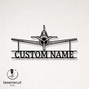 May include: A black metal wall sign featuring a front-facing propeller airplane silhouette positioned above a horizontal bar with the text CUSTOM NAME in a serif font. The design includes two vertical supports connecting the plane to the name bar.