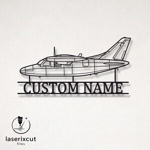 May include: A black metal wall art piece featuring the silhouette of a twin-engine airplane. Below the aircraft, two horizontal lines frame the text "CUSTOM NAME" in a serif font. The design is connected by vertical supports.