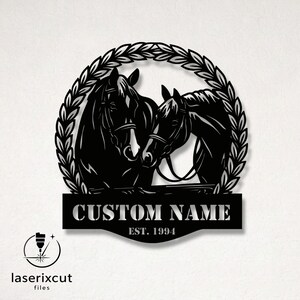 Puede incluir: Arte de pared de metal negro con dos caballos dentro de una corona de laurel. El diseño incluye el texto "CUSTOM NAME" y "EST. 1994" en una pancarta debajo. El logotipo de laserxcut files está en la esquina inferior izquierda.