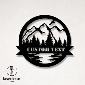 Peut inclure: Décoration murale en métal noir représentant un paysage de montagne avec des arbres et des oiseaux, dans un cadre circulaire. Le texte "CUSTOM TEXT" est affiché sur une bannière. Idéal pour la décoration intérieure.