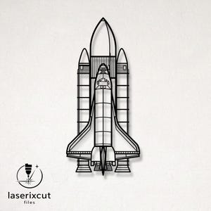 May include: A black line art illustration of a space shuttle featuring a central orbiter flanked by two solid rocket boosters and an external fuel tank. The design includes detailed structural paneling and engine nozzles at the base.