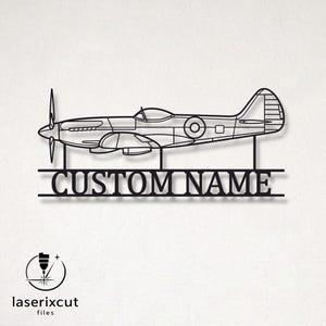 Puede incluir: Una pieza de arte mural de metal negro con la silueta de perfil de un avión de hélice. Debajo de la aeronave, dos líneas horizontales enmarcan el texto CUSTOM NAME en una fuente serif negrita. El diseño se une mediante soportes verticales.