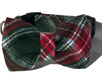 May include: A green, red, and white plaid dog collar with a matching bow tie. The collar has a black plastic buckle and a silver metal D-ring. The bow tie is centered on the collar.