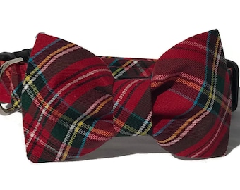 May include: Red plaid dog collar with a matching bow tie. The collar features a classic tartan pattern in red, green, yellow, and white. The bow tie is centered on the collar, and the hardware is silver and black.
